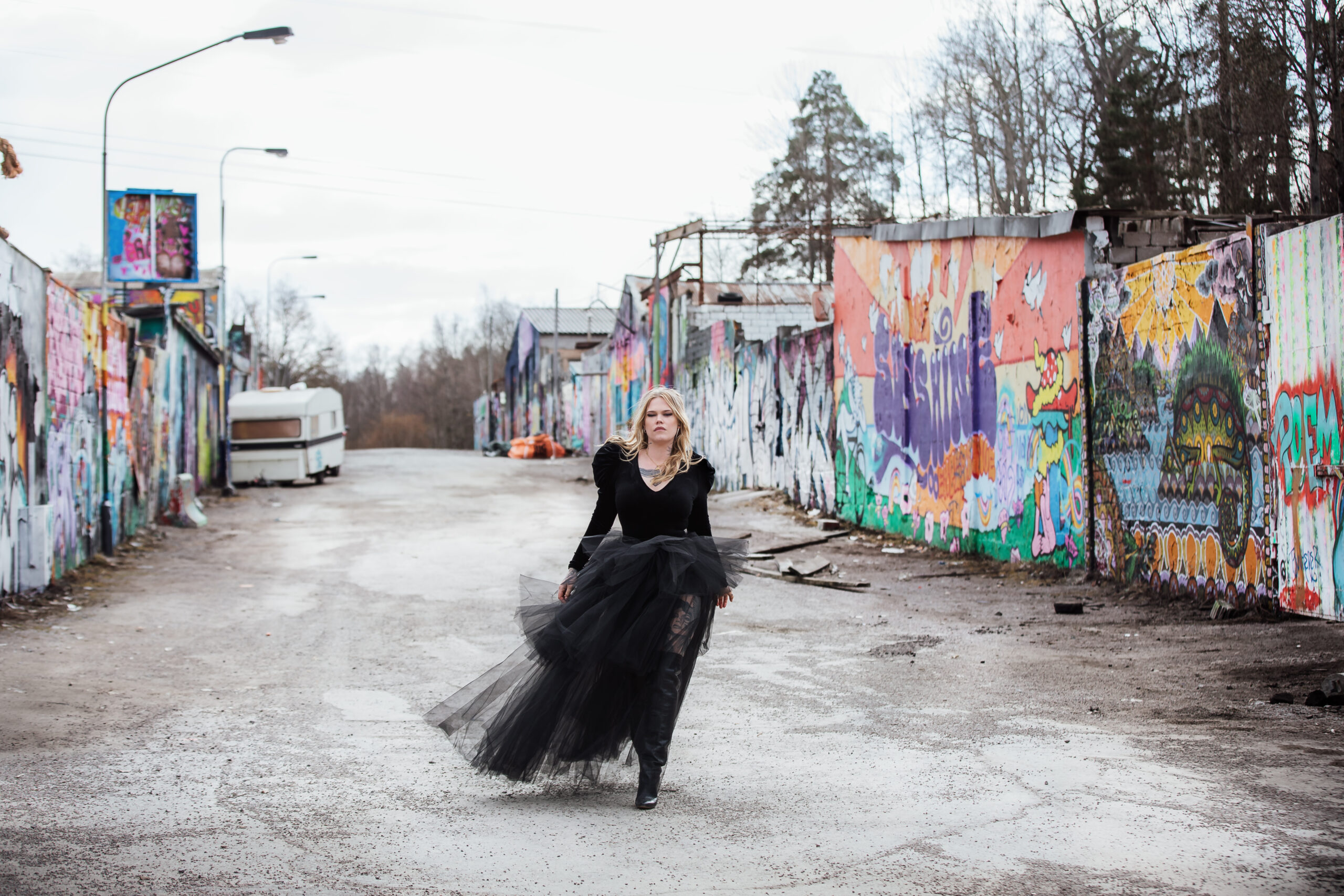 Bild på Julia Frej i svart klänning bland graffiti. Fotograf är Johanna Gunnberg