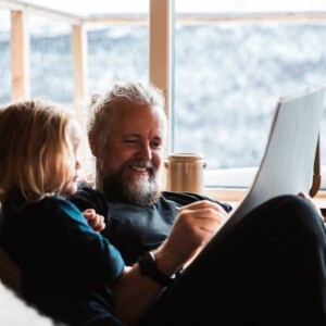 Porträttbild på KOnrad Bergström som sitter ocj läser för ett barn