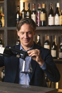 Porträttbild på Coravins grundare Greg Lambrecht hällandes vin i ett glas