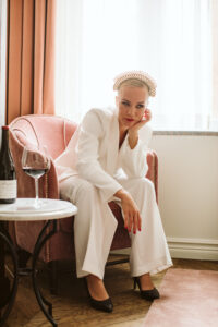 porträttbild på Karin Ericson i vita klder med ett glas rött vin. Foto: Lina Arvidsson