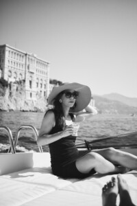 Svartvit porträttbild på Samanda Ekman i Roquebrun, Frankrike med med stor hatt på en båt.