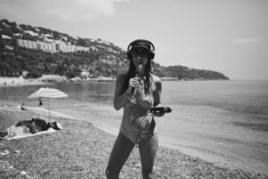 Svartvit porträttbild på Samanda Ekman på en strand hållandes i en mikrofon.