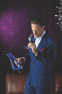 Maximilian Riedel doftar på vin ur ett glas med karaffen Veloce Amadeo Blue i handen
