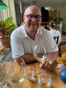 Porträttbild på Davif Favaro med ett glas vin i handen vid ett bord