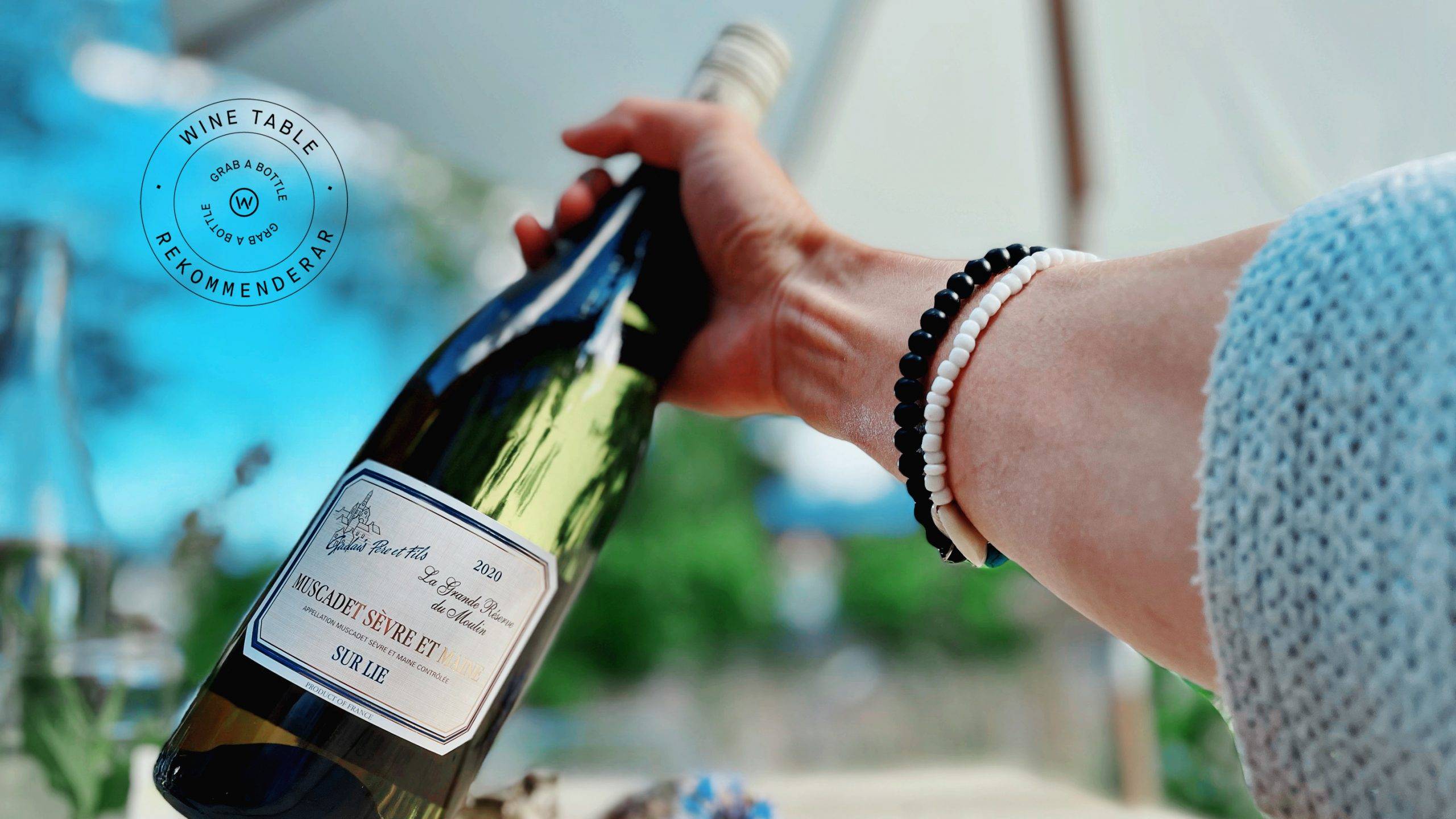 Bild på Grab a Bottle – viner njuta i brisen från havet under ett stort vitt parasoll